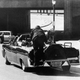 Clint Hill leaps onto the back of the presidential limo as Jacqueline Kennedy stands up after her husband was shot.